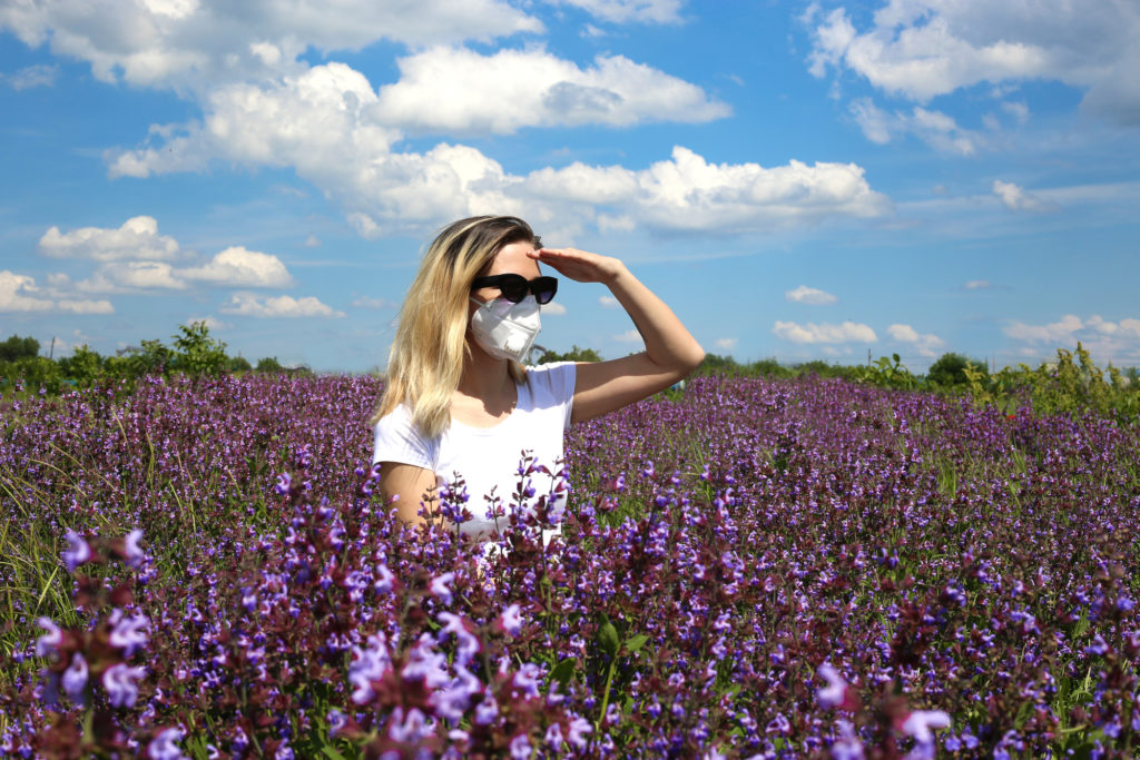 Woman wearing reusable face mask in field of flowers